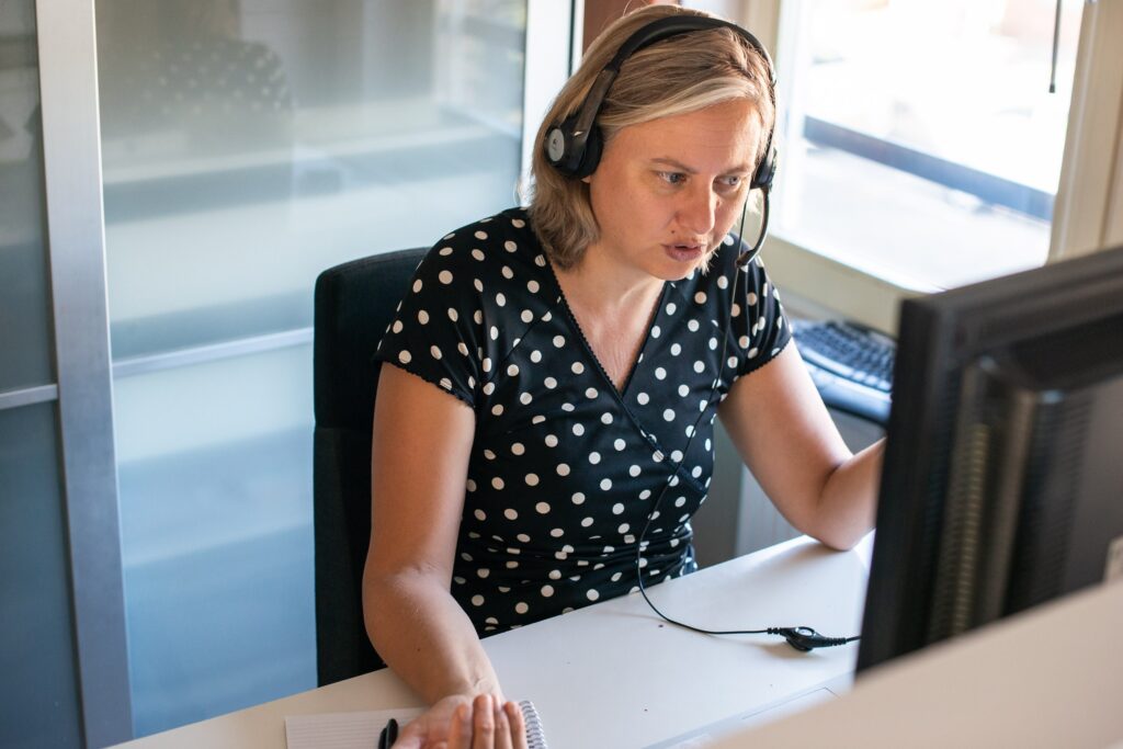 Paulien Bruijn giving an online training. Sitting behind computer screen with headset on.